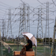 A man sits in the shade of his umbrella at the Dog Park under high tension power lines in Redondo Beach, California on Aug. 16, 2020. California ordered rolling power outages for the first time since 2001 as a statewide heat wave strained its electrical system.